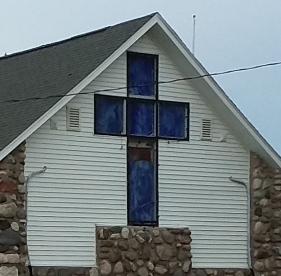 Image of the front of the stone church with the large blue glass cross.